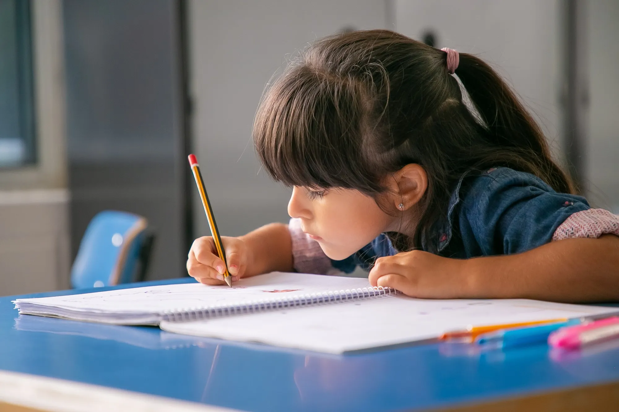 Focused Haired Latin Girl Sitting School Desk Drawing Her Copybook